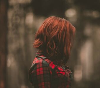 A imagem mostra uma moça de perfil, com o cabelo vermelho cortado no estilo long bob.