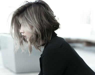 A imagem mostra uma moça de perfil, com o cabelo loiro acinzentado cortado no estilo long bob.