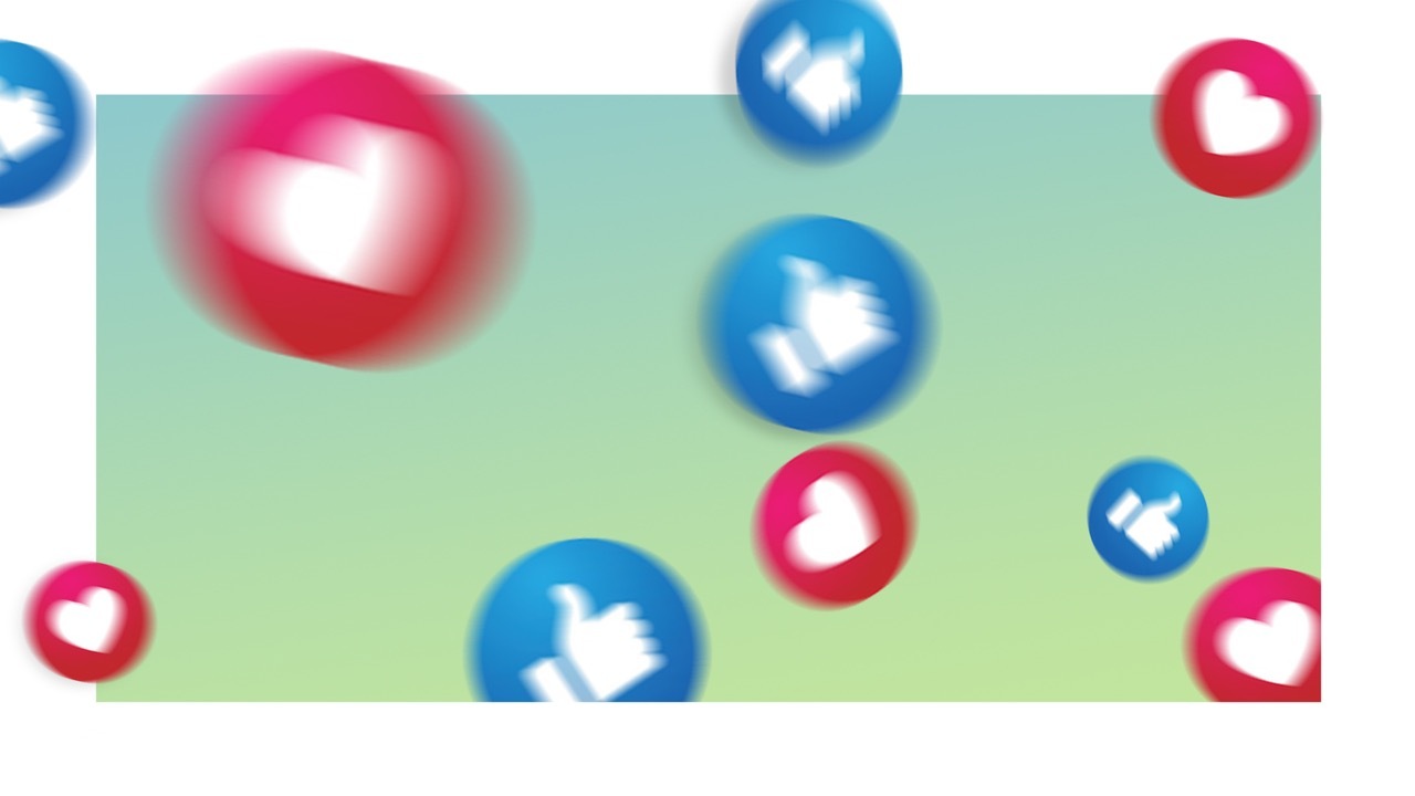 A imagem mostra dois ícones diferentes um deles sendo um círculo azul com uma mão em branco no formato positivo, demonstrando um like, e a outra um círculo vermelho com um coração branco, demonstrando uma opção de interação “amei”, típicas de uma rede social.